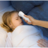 a hand holding a thermometer to a young girl lying down